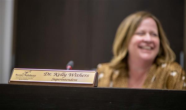 Dr. Withers smiles at a board meeting. Her name plate is in front of her
